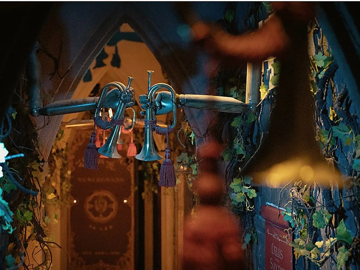 Brass trumpets and blue light around an ornate doorway in AURORA.